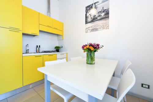a kitchen with yellow cabinets and a white table with flowers at Campeggio Europa Silvella in San Felice del Benaco