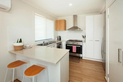a kitchen with white cabinets and a counter with stools at Northside Townhouse Geelong in Norlane