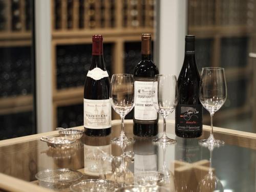 three bottles of wine sitting on a table with wine glasses at HOTEL de L'ALPAGE in Chino