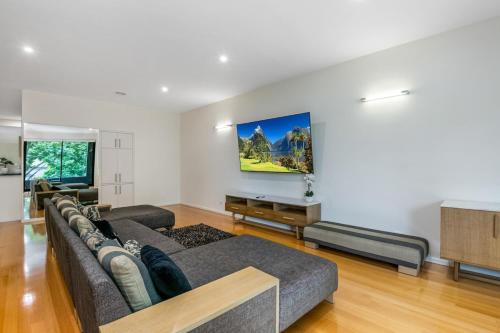 a living room with a couch and a flat screen tv at Serpentine Park on View in Bendigo