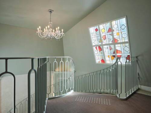a staircase with a chandelier and a stained glass window at HOTEL de L'ALPAGE in Chino