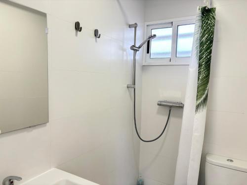 a bathroom with a shower and a toilet and a window at Escápate al Sol Apartamento con Piscina y Playa Cercana in Playa Pobla de Farnals