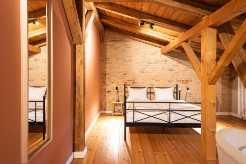 an attic bedroom with a bed and a brick wall at Storchenhof Blumenow in Blumenow