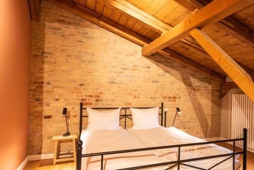 a bed in a room with a brick wall at Storchenhof Blumenow in Blumenow