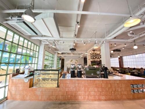 a restaurant with a counter in a large room with windows at Beat Hotel Bangkok in Bangkok