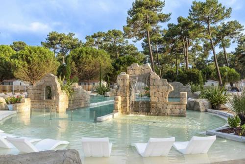 un parc aquatique avec des chaises blanches et une fontaine dans l'établissement Camping 4 étoiles - Parc aquatique - eeibed, à Vendays-Montalivet