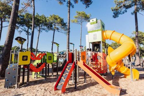 une aire de jeux avec toboggan jaune dans un parc dans l'établissement Camping 4 étoiles - Parc aquatique - eeibed, à Vendays-Montalivet