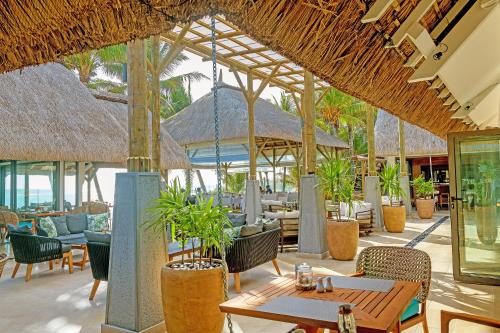 an outdoor restaurant with tables and chairs and trees at Seasense Boutique Hotel & Spa in Belle Mare