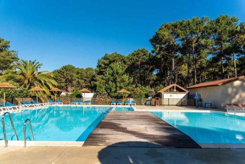 une piscine dans un complexe avec des arbres en arrière-plan dans l'établissement Camping 4 étoiles - Parc aquatique - eeic0f, à Biscarrosse