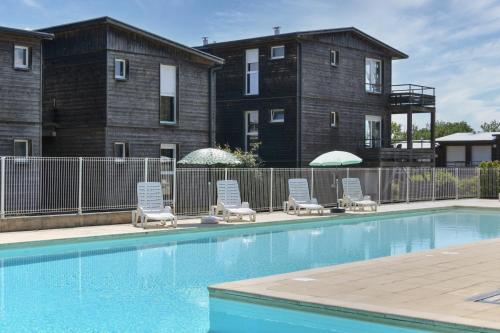 a pool with chairs and umbrellas in front of a building at Vacancéole - Domaine de Saint Orens in Montréal