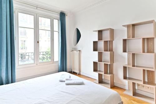 une chambre blanche avec un lit et une fenêtre dans l'établissement Appartement Haussmannien lumineux et central- II, à Paris