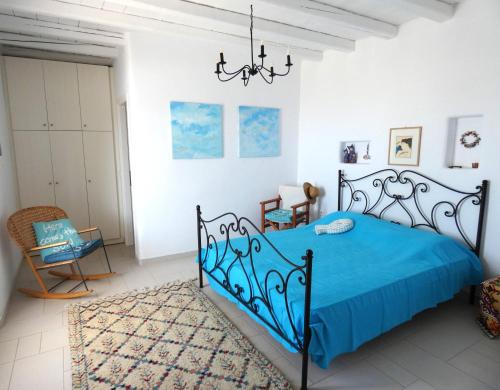 een slaapkamer met een blauw bed en een kroonluchter bij La Casa dei Gatti Paros in Kalami