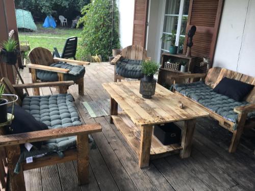 un patio avec des canapés et une table et des bancs en bois dans l'établissement Chambre d'hôtes Sous Les Grands Chênes BOHEME, à Saint-Étienne-de-Corcoué