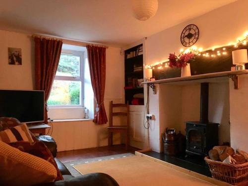 ein Wohnzimmer mit einem Kamin und einem Fenster in der Unterkunft HOLIDAY HOUSE TANYGRISIAU SNOWDONIA North Wales in Tanygrisiau