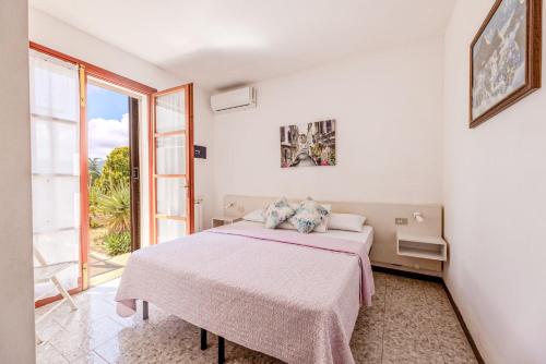 a white bedroom with a bed and a large window at Capo Ai Pini - Bilo Elisa in Lacona