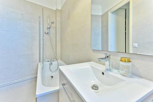 une salle de bain blanche avec un lavabo et un miroir dans l'établissement Évasion parisienne Monceau & Arc de Triomphe - II, à Neuilly-sur-Seine
