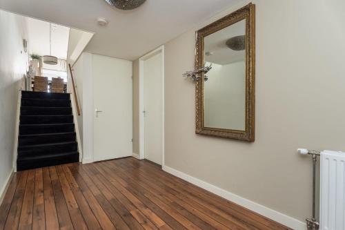 a hallway with a mirror on the wall and a staircase at Kabbelaarsbank 405 - Port Marina Zélande NOT INTENDED FOR COMPANY OR WORK-RELATED STAYS in Ouddorp
