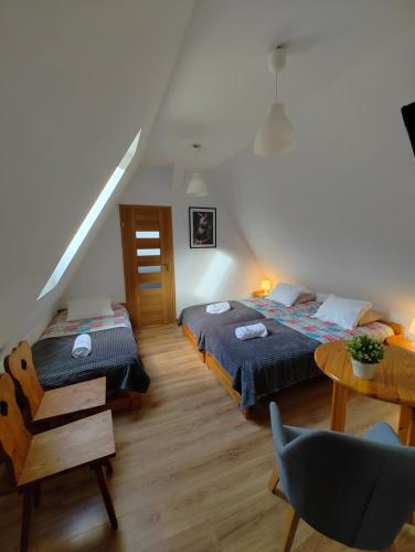 a bedroom with two beds and a table and a chair at Zającówka in Polanica-Zdrój
