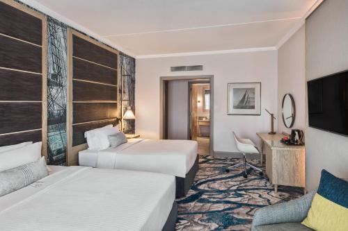 a hotel room with two beds and a desk at Le Suffren Hotel & Marina in Port Louis
