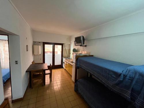 a bedroom with a bed and a desk and a kitchen at El Dorado Deptos a una cuadra del mar in San Bernardo