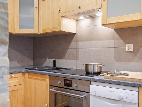 une cuisine avec des armoires en bois et un four à plaques de cuisson dans l'établissement Apartment Le Petit Savoyard-4 by Interhome, à Châtel