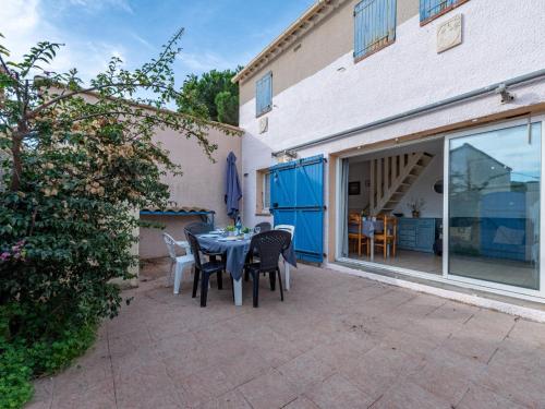 un patio avec une table et des chaises à côté d'un bâtiment dans l'établissement Holiday Home Les Jardins du Barcarès-1 by Interhome, au Barcarès