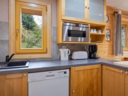 La cuisine est équipée de placards en bois, d'un évier et d'un four micro-ondes. dans l'établissement Apartment Le Petit Savoyard-3 by Interhome, à Châtel
