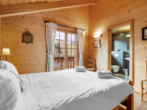 a bedroom with a white bed in a log cabin at Chalet Godfrey by Interhome in Les Crosets