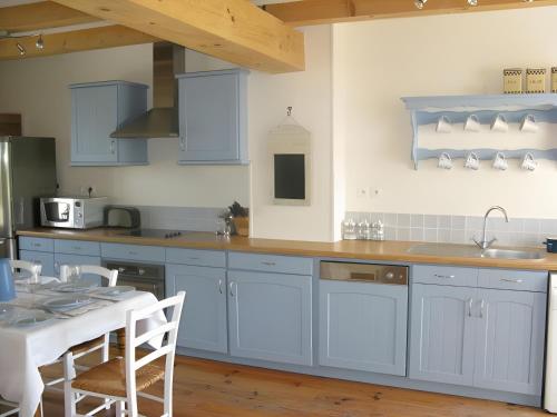 a kitchen with blue cabinets and a table and a table and chairs at Ambre à la Rochelle in Vergné