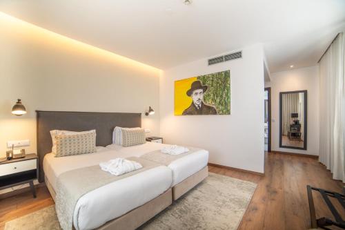 リスボンにあるVIP Executive Picoas Hotelの大きなベッド付きのベッドルーム1室、壁に絵画が飾られています。