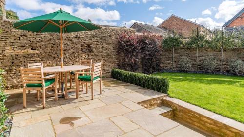 eine Terrasse mit Tisch und Stühlen und einem Sonnenschirm in der Unterkunft Tachbrook in Charlbury