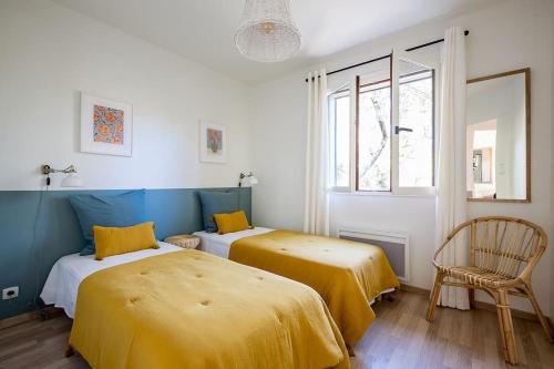 Cette chambre comprend 2 lits avec des draps jaunes et une chaise. dans l'établissement Villa Fougères à deux pas de la plage PYLA SUR MER, à La Teste-de-Buch