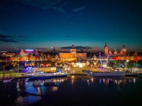 a city lit up at night with boats in the water at Grand Park Hotel in Szczecin