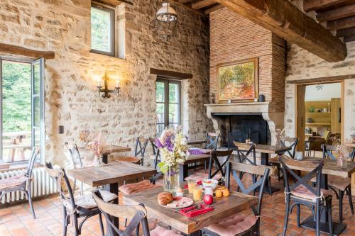 a dining room with tables and chairs and a fireplace at Demeures et Châteaux Moulin des Templiers Hôtel & SPA in Pontaubert