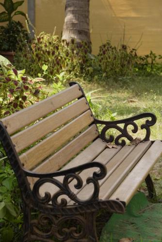 a wooden bench sitting in the grass next to a tree at Coco inn Goa in Candolim