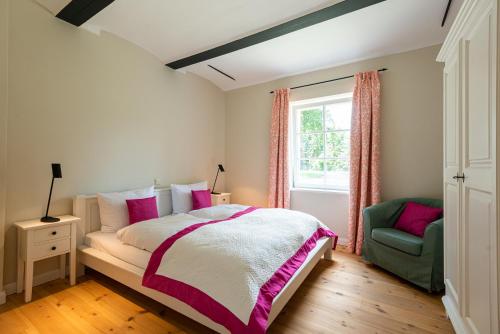 a bedroom with a bed and a chair and a window at Storchenhof Blumenow in Blumenow
