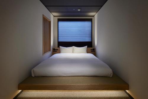 a bedroom with a white bed with a window at Minn Asakusa Kuramae North in Tokyo