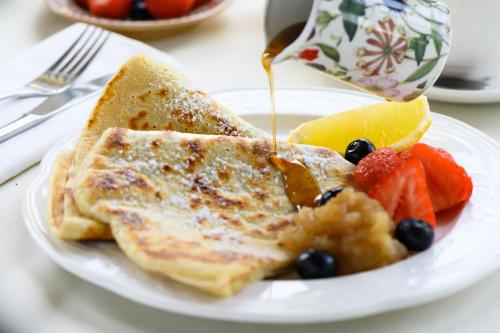 a plate of pancakes with fruit and a cup of coffee at Killarney Lodge in Killarney