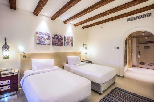 two beds in a room with white walls and wooden ceilings at Hilton Marsa Alam Nubian Resort in Abu Dabab