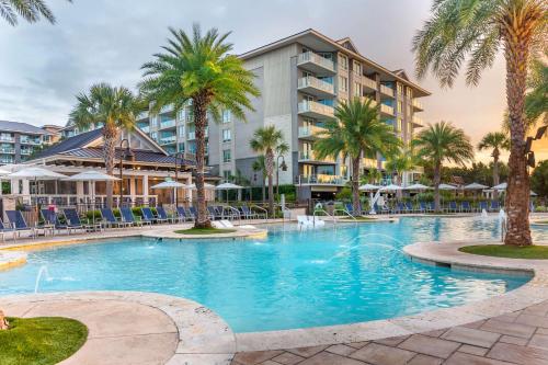 a large swimming pool with palm trees and a building at Hilton Grand Vacations Club Ocean Oak Resort Hilton Head in Hilton Head Island