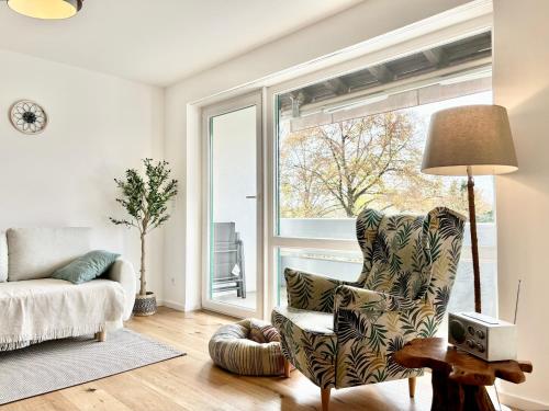 a living room with a chair and a large window at Snug Stays 5 - Design Apartment mit Sonnenbalkon, ruhig, zentral in Herrsching am Ammersee