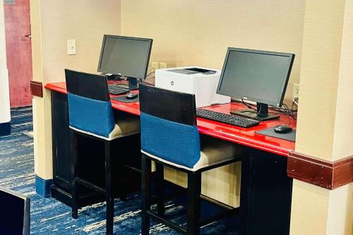 a desk with three computer monitors on top of it at Comfort Inn & Suites in Jackson