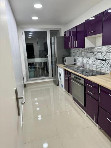 Il comprend une cuisine avec des placards violets et du carrelage blanc. dans l'établissement Paris La Défense, à Puteaux