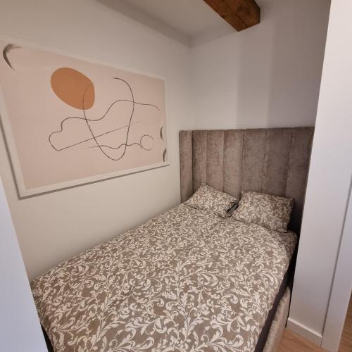 Una cama en un dormitorio con un cuadro en la pared. en Apartament Centrum 4, en Leszno