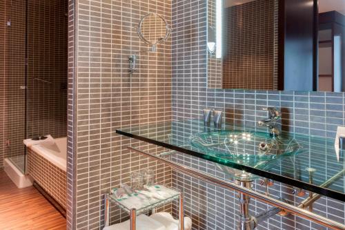 a blue tiled bathroom with a sink and a toilet at AC Hotel by Marriott Madrid Airport in Coslada