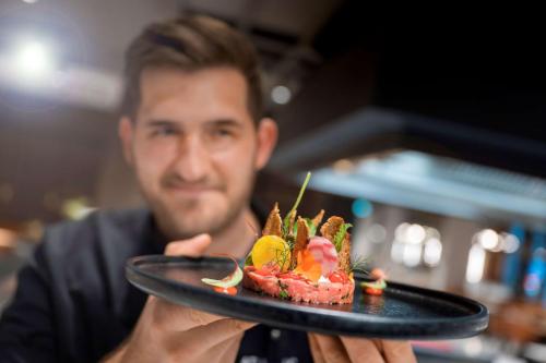 a man holding a black plate with food on it at ATLANTIC Hotel Münster in Münster