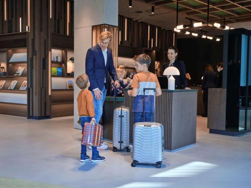a man and two boys with luggage in a store at ATLANTIC Hotel Münster in Münster