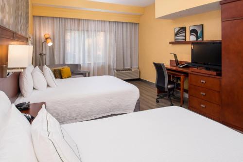a hotel room with two beds and a desk with a computer at Courtyard by Marriott Victorville Hesperia in Hesperia