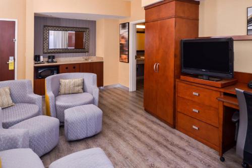 a living room with two chairs and a television at Courtyard by Marriott Victorville Hesperia in Hesperia