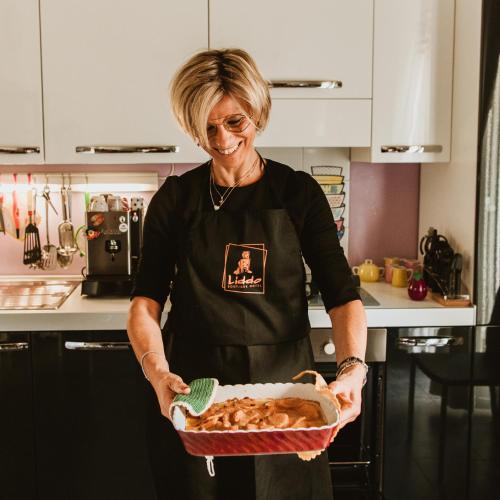 a woman holding a basket of food in a kitchen at Liddo Boutique hotel in Barletta